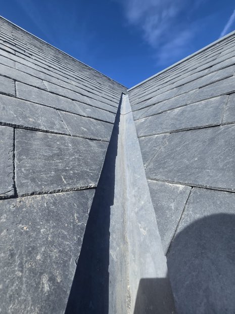 Two Spanish slate roof planes meeting at a dressed lead valley in Barby, Warwickshire