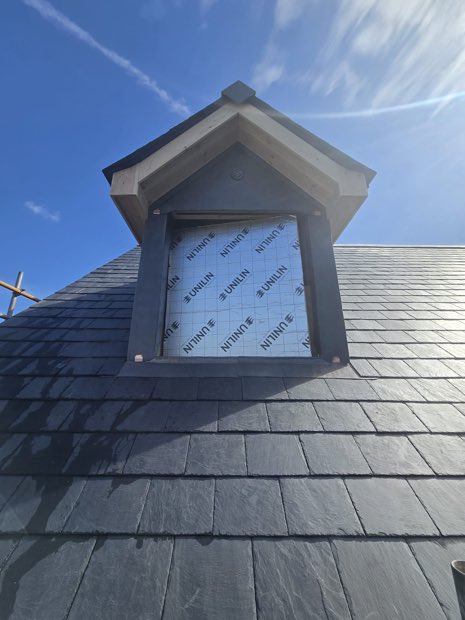 Close-up of a bespoke lead dormer with dressed lead cheeks and copper clips on a Spanish slate roof in Barby